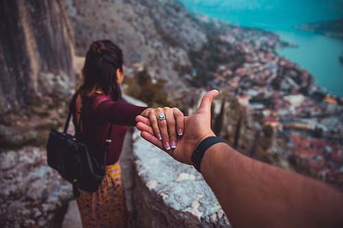 holding hands woman holding man's hand while looking on scenery of building beside body of water during daytime human